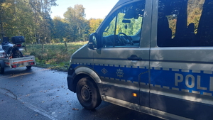 na zdjęciu radiowóz na ulicy, przed nim na przyczepie motocykl