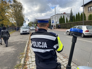 na zdjęciu policjant przy motocyklu obserwuje drogę