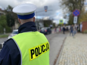 na zdjęciu policjant w odblaskowej kamizelce obserwuje drogę