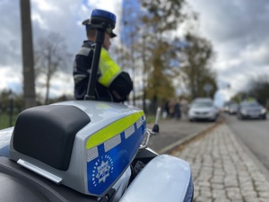 na zdjęciu policjant przy motocyklu obserwuje drogę