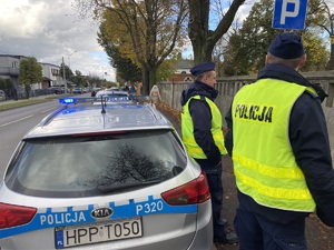 na zdjęciu policjanci na chodniku przy radiowozie