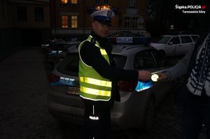 na zdjęciu policjant wręczający osobie odblask