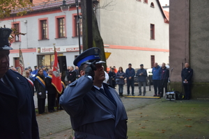 na zdjęciu komendant powiatowy oddający honor pod pamiątkową tablicą