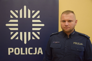 policjant przy banerze z napisem policja
