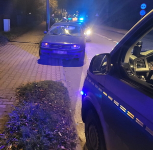 na zdjęciu policyjne radiowozy i zatrzymany do kontroli samochód pomiędzy nimi