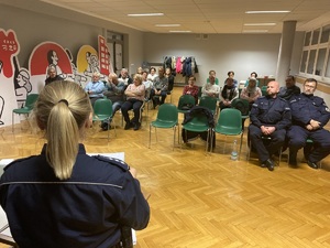 na zdjęciu policjantka przed osobami siedzącymi na sali