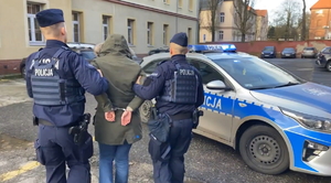 na zdjęciu policjanci prowadzą zatrzymaną do radiowozu