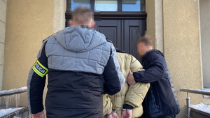na zdjęciu policjanci wprowadzają zatrzymanego do budynku komendy
