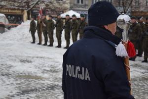 Na zdjęciu widoczny policjant z żołnierzami w tle