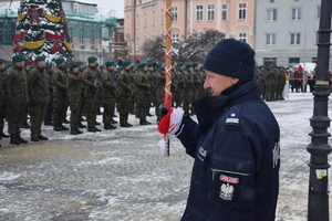 Na zdjęciu widoczny policjant z żołnierzami w tle