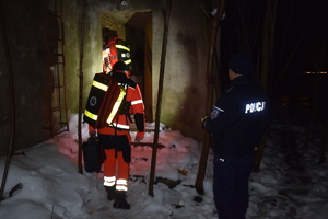 Na zdjęciu widoczny policjant i ratownicy medyczni wchodzący do pustostanu
