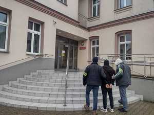 Na zdjęciu widoczni policjanci w cywilnych ubraniach wraz z zatrzymanym