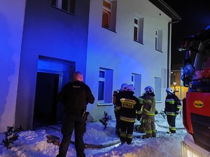 na zdjęciu policjant i strażacy przed budynkiem
