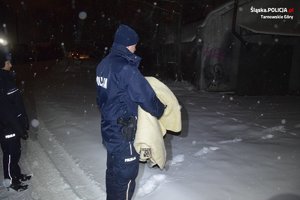 na zdjęciu policjant trzymający w ręku koc
