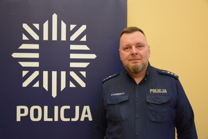 na zdjęciu dzielnicowy Konieczny przy banerze z napisem policja