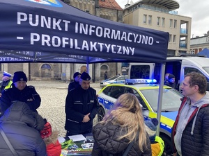 na zdjęciu policyjny namiot z napisem punkt informacyjno - profilaktyczny, pod nim policjanci, przed osoby, a obok radiowóz