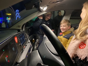 na zdjęciu dzieci w radiowozie, a przy nich, w drzwiach pasażera, policjant machający ręką do aparatu