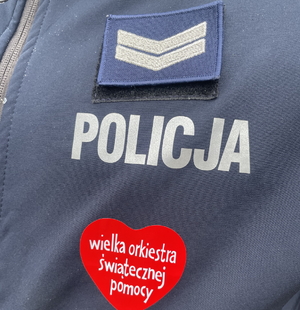 na zdjęciu fragment munduru z napisem policja i serduszkiem wielkiej orkiestry świątecznej pomocy