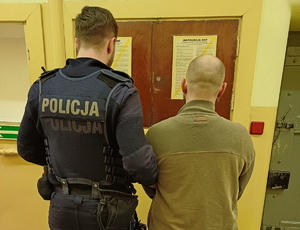 na zdjęciu policjant trzyma za ramię zatrzymanego