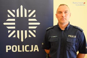 na zdjęciu dzielnicowy Bugajski przy banerze z napisem policja