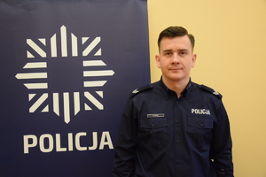 na zdjęciu dzielnicowy Mazur przy banerze z napisem policja