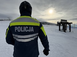 na zdjęciu policjant w stroju narciarskim i kasku tyłem do aparatu