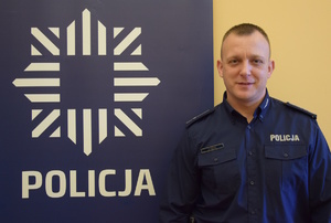 na zdjęciu dzielnicowy Cieślik przy banerze z napisem policja