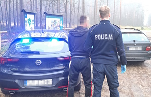 na zdjęciu policjant z zatrzymanym przy nieoznakowanym radiowozie, obok którego stoi czarne bmw