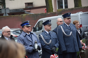 na zdjęciu komendant policji ze zniczem w ręku, obok burmistrz miasta i przedstawiciele służby więziennej