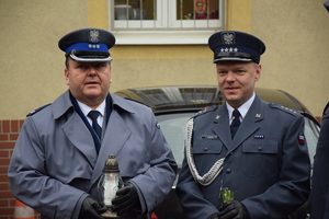 na zdjęciu komendant policji ze zniczem i przedstawiciel służby więziennej z kwiatami