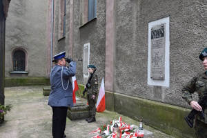 na zdjęciu komendant policji oddający honor pod pamiątkową tablicą