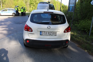 na zdjęciu biały samochód a przed nim radiowóz i policjanci