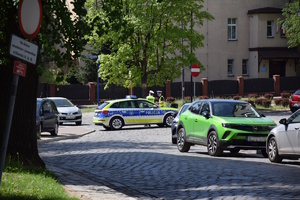 na zdjęciu radiowóz blokujący drogę, obok niego policjanci i inne pojazdy