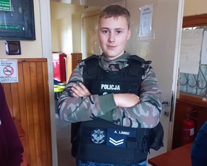 na zdjęciu dziecko w policyjnej kamizelce w pomieszczeniu
