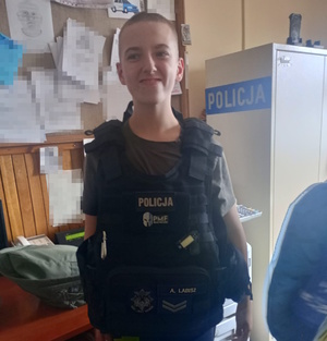 na zdjęciu dziecko w policyjnej kamizelce w pomieszczeniu