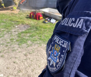 na zdjęciu ramię policjanta, przed nim zbiornik na zborze