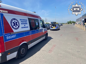 na zdjęciu karetka pogotowia i radiowóz na parkingu przed sklepem