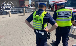 na zdjęciu policjanci na parkingu przed sklepem, obok karetka pogotowia