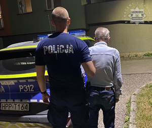 na zdjęciu policjant z zatrzymanym przy radiowozie
