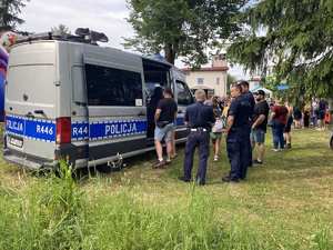 na zdjęciu policjanci przy radiowozie, obok dzieci z rodzicami