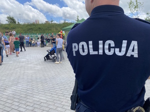 na zdjęciu policjant tyłem do aparatu, przed nim uczestnicy pikniku