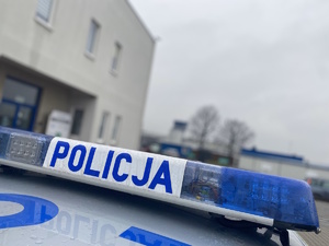 na zdjęciu fragment dachu radiowozu gdzie widoczny neon policyjny, a za nim fragment budynku