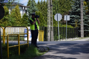 na zdjęciu policjant przy drodze z miernikiem prędkości