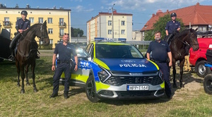 na zdjęciu policjanci przy radiowozie, obok policjanci na koniach