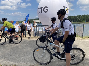 na zdjęciu dwaj policjanci na rowerach przy terenie imprezy