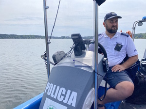 na zdjęciu policjant za sterami motorówki policyjnej