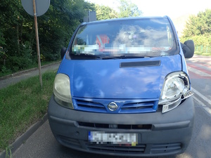 na zdjęciu niebieski bus na jezdni z uszkodzonym reflektorem prawym i przednią szybą