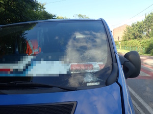 na zdjęciu fragment niebieskiego busa z uszkodzoną przednią szybą