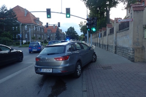 na zdjęciu samochód z uszkodzonym przodem na barierce chodnikowej, obok inne pojazdy