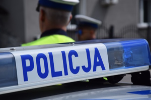 na zdjęciu policyjny neon, a za nim policjanci w białych czapkach